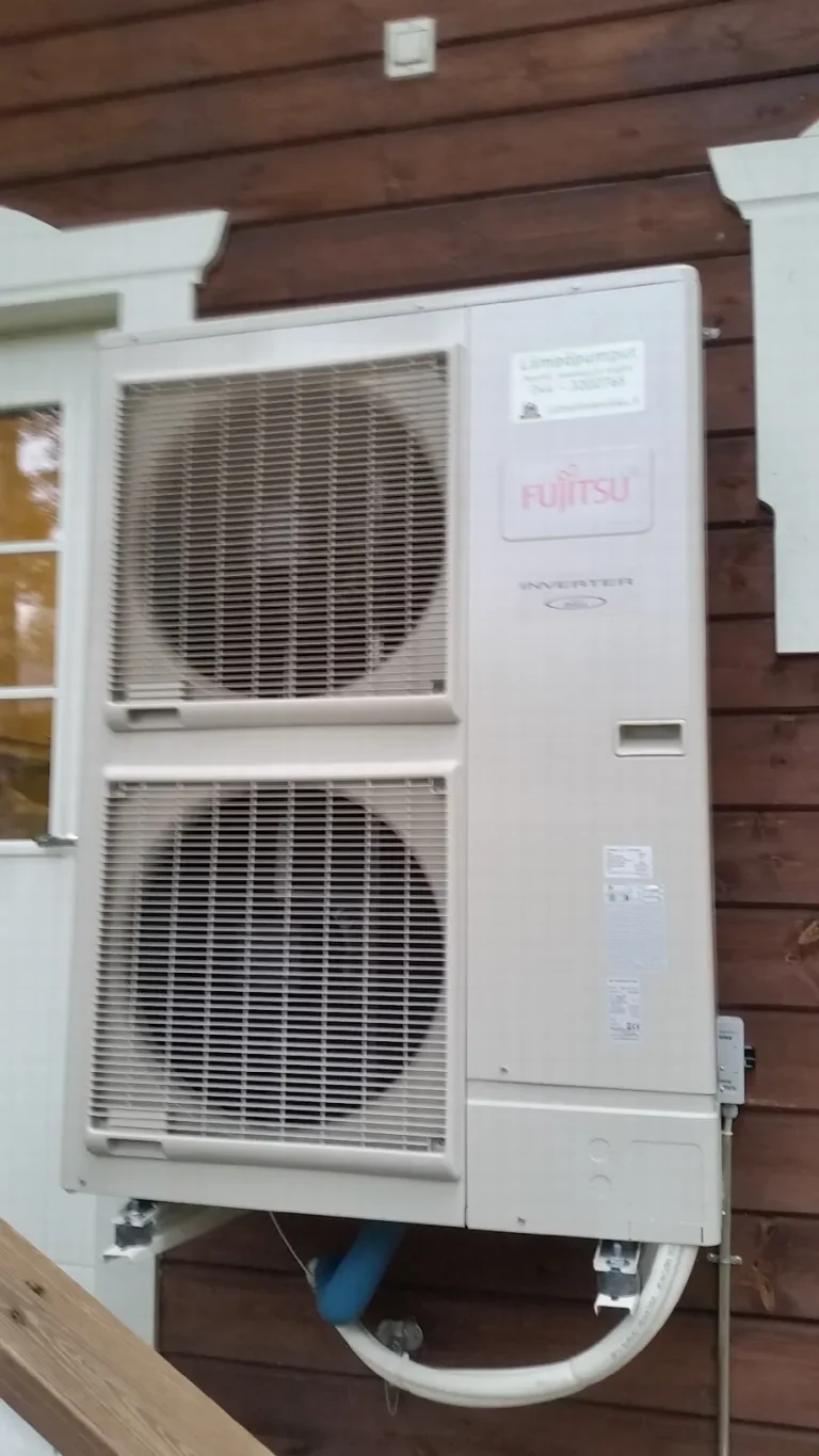 Fujitsu-ilma-vesilämpöpumpun ulkoyksikkö punaruskealla puuseinällä