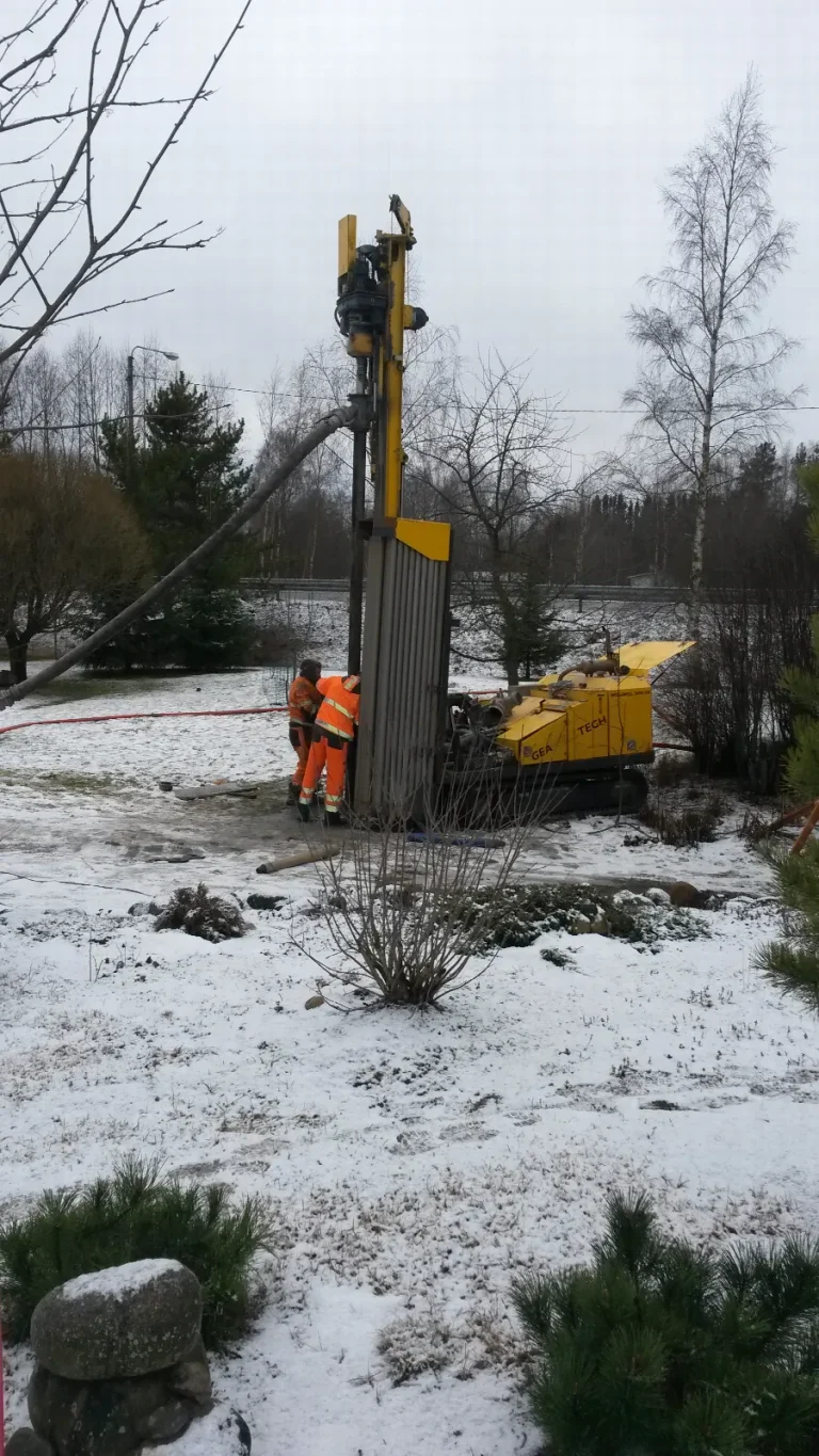 Porauskone poraa lämpökaivoa lumisessa pihassa